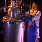 Researcher Jong Baik next to a hydrogen densification experiment in a lab, photo