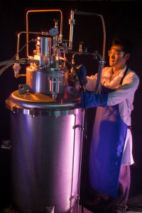 Researcher Jong Baik next to a hydrogen densification experiment in a lab, photo