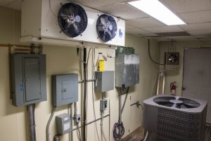 Laboratory testing air conditioning unit, with fans and electrical panels on wall, photo.