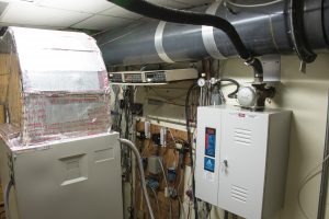 Laboratory testing air conditioning unit and ducts, with valves and thermostats on wall, photo.