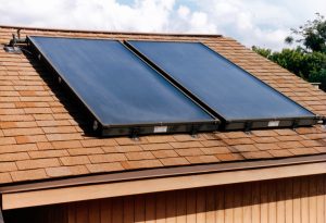 Two solar water heating panels on brown single roof.