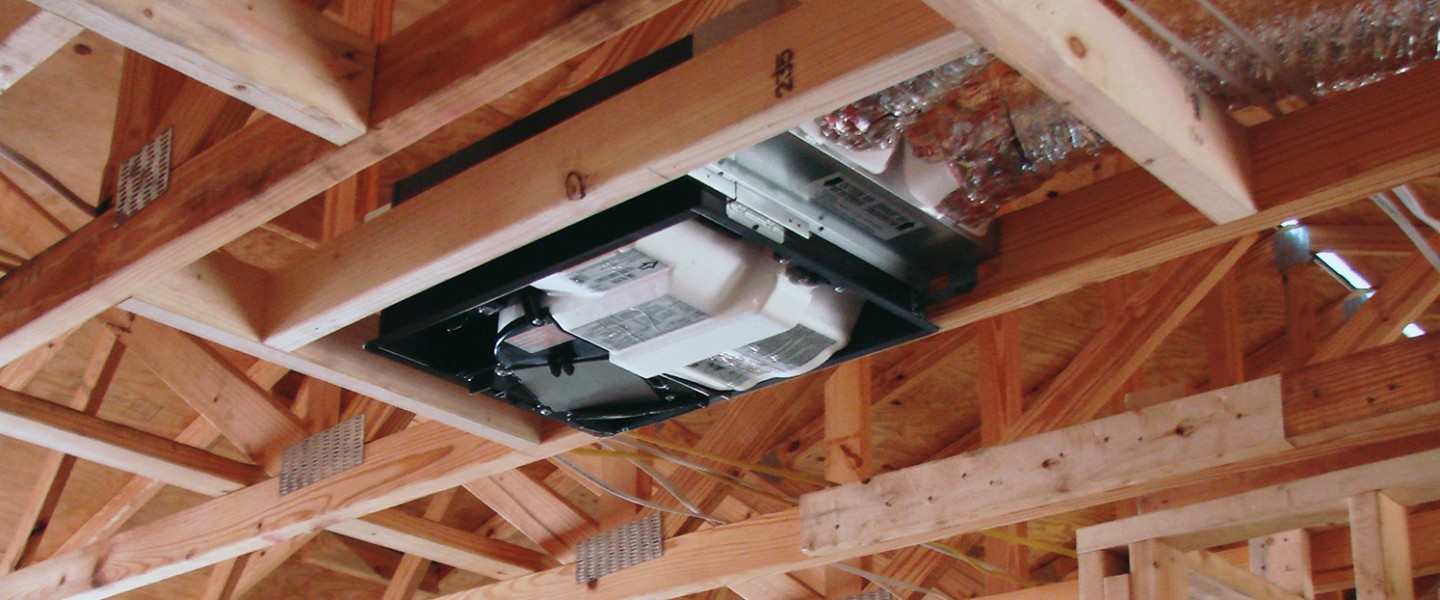 An Energy Recovery Ventilator (ERC) mounted in the wooden rafters of a new residential home under construction.