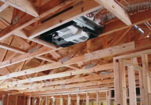 An Energy Recovery Ventilator (ERC) mounted in the wooden rafters of a new residential home under construction.