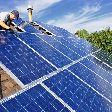 Man installing alternative energy photovoltaic solar panels on roof.