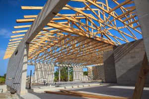 New home construction, cement block walls with wooden roof truss. Roof open with blue sky.