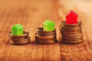 Real estate mortgage concept with small plastic house models on top of stacked coins.