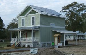 Newly-constructed factory-built modular, two-story home with covered porch and photovoltaic panels on roof.