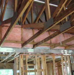 Unfinished interior of house showing trusses with ducts constructed in a raised ceiling.