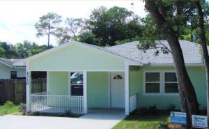 Single story house with light colored shingle roof and covered porch over front door and part of house.