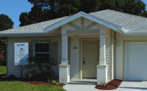 Single-story house with light colored shingled roof, two car garage, columns at entrance.