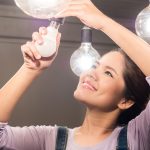 Asian woman changing light bulb