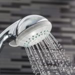 Silver shower head on a bathroom with water drops falling on a bathroom textured background