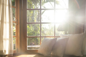 Living room windows with part of sofa in sunny day and white cushion interior background concept.