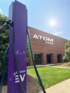 Atom Power charging station (purple in color) in front of Atom Energy's brick office building.